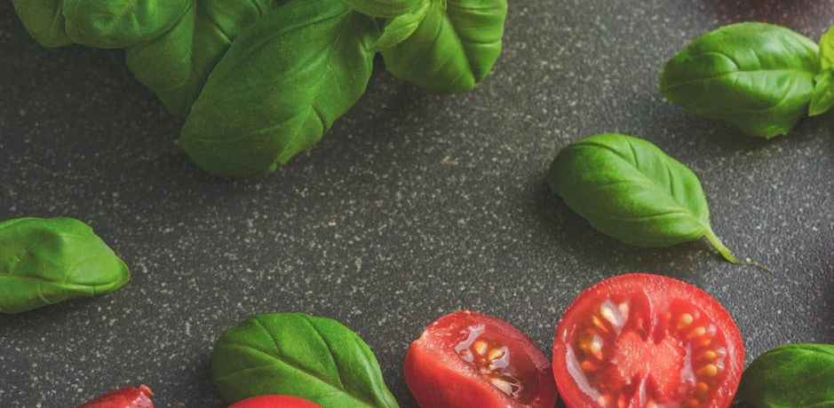 photography of tomatoes near basil leaves